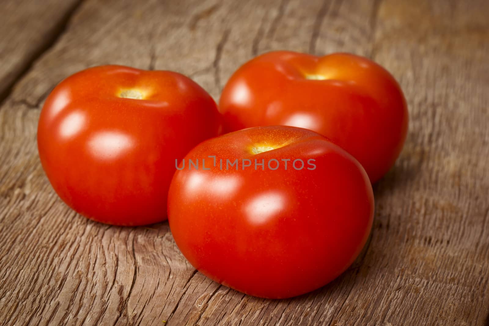 Three ripe tomatoes on wooden background