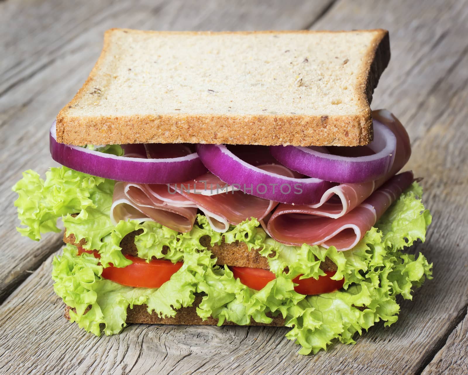 Parma ham sandwich with vegetables on wooden table