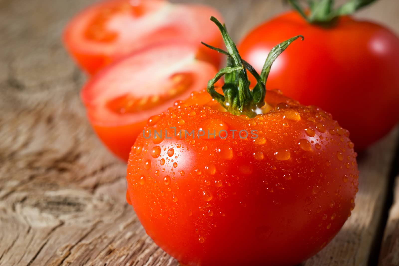 Closeup view of tomatoes with water drops on wooden background