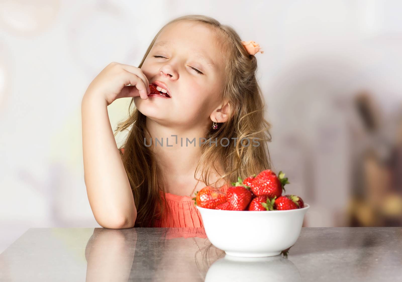 Little girl with strawberry at the table