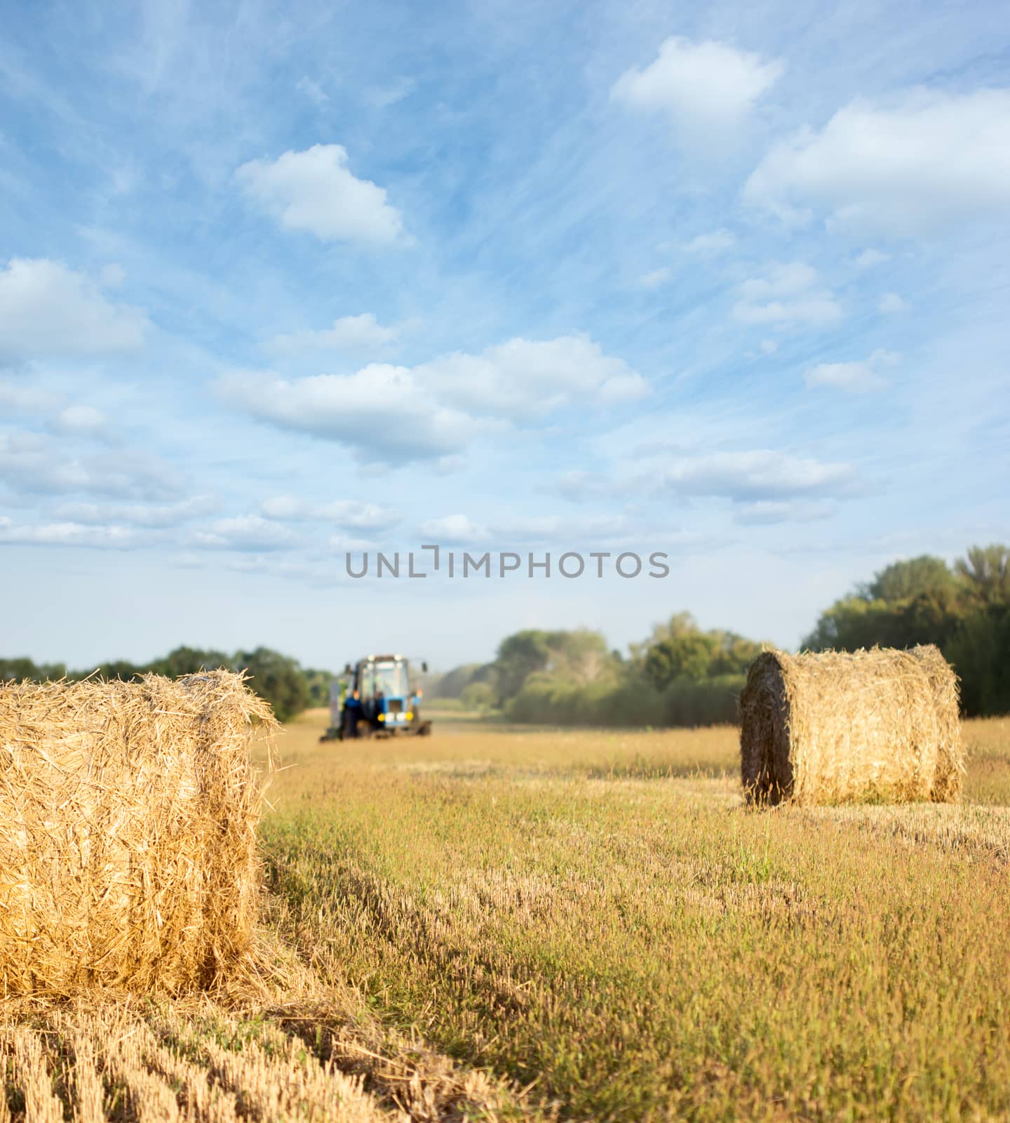 Tractor throwing out hay roll