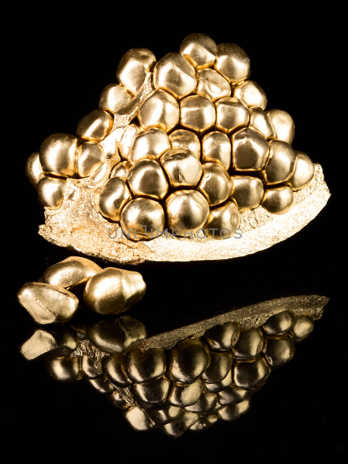Piece of pomegranate in gold on black background