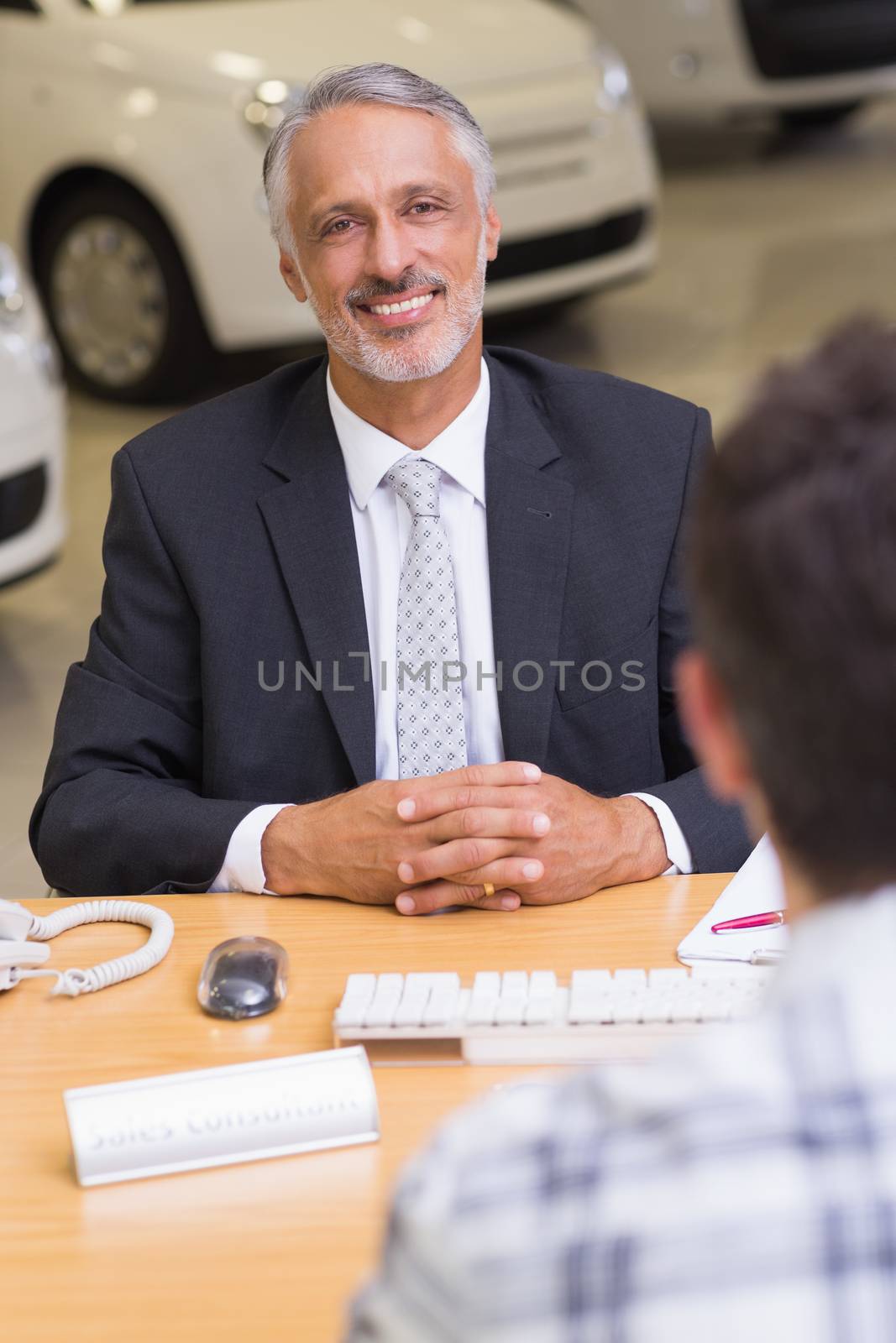 Smiling businessman looking at camera at new car showroom