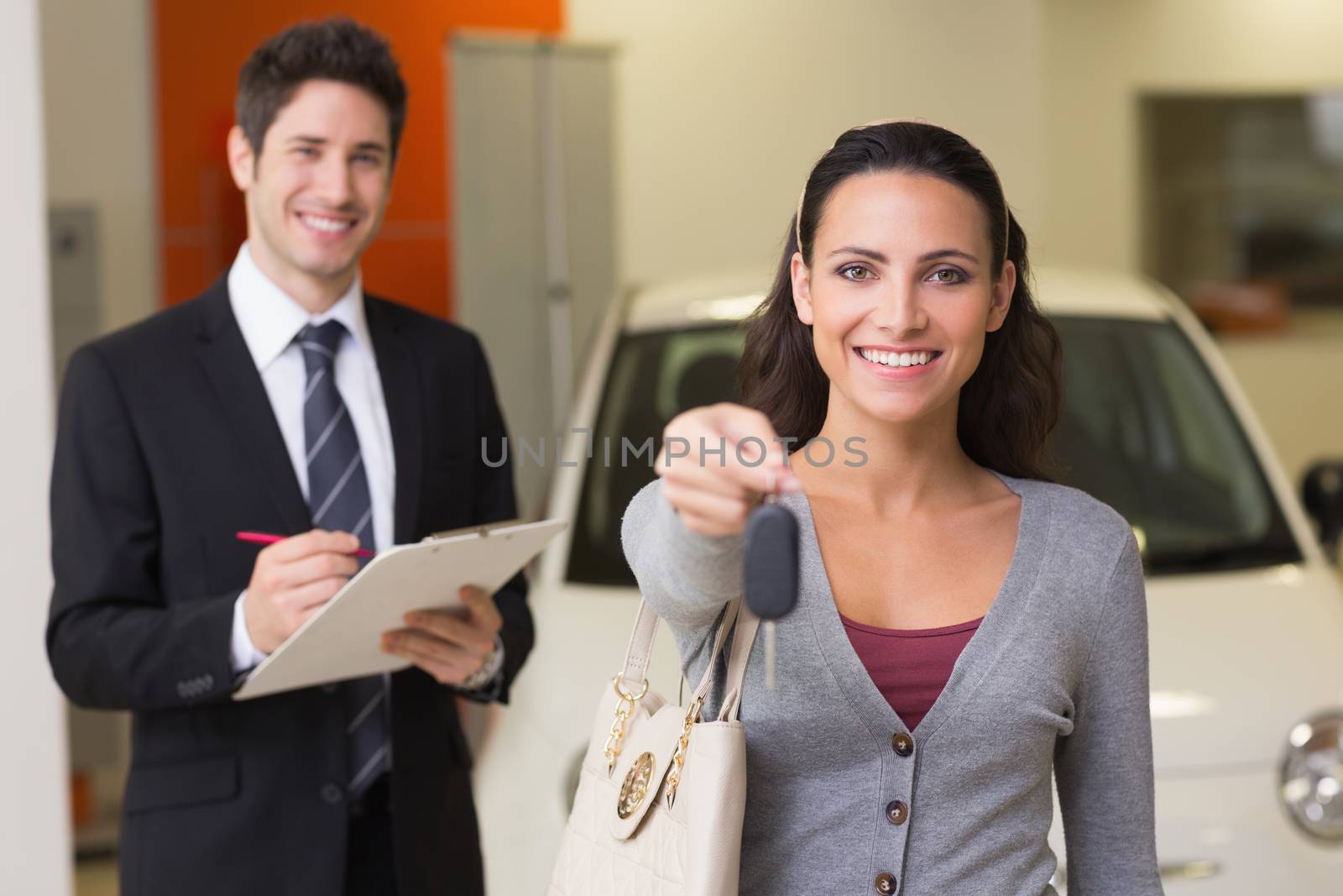 Happy customer holding a car key at new car showroom