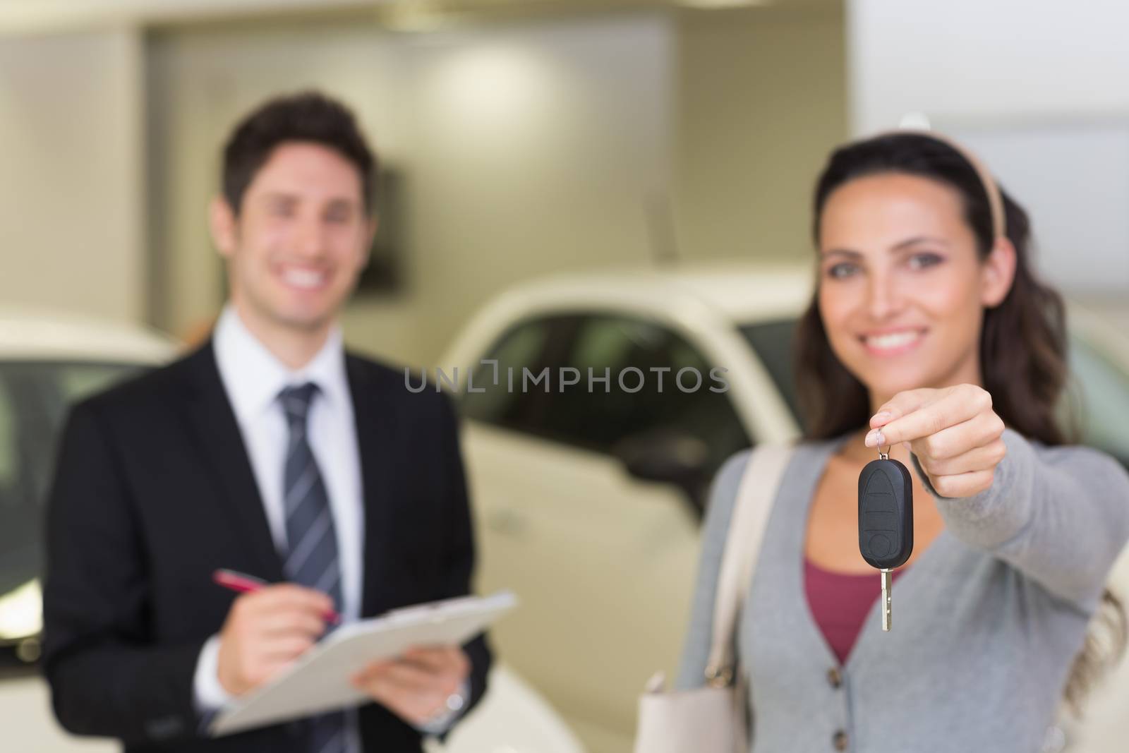 Female driver showing a key after bying a new car at new car showroom