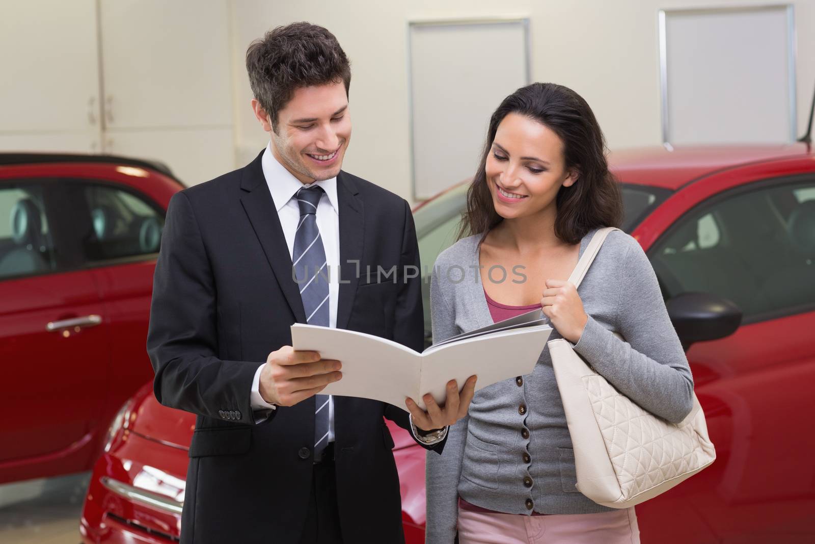 Salesman showing brochure to customer and smiling by Wavebreakmedia