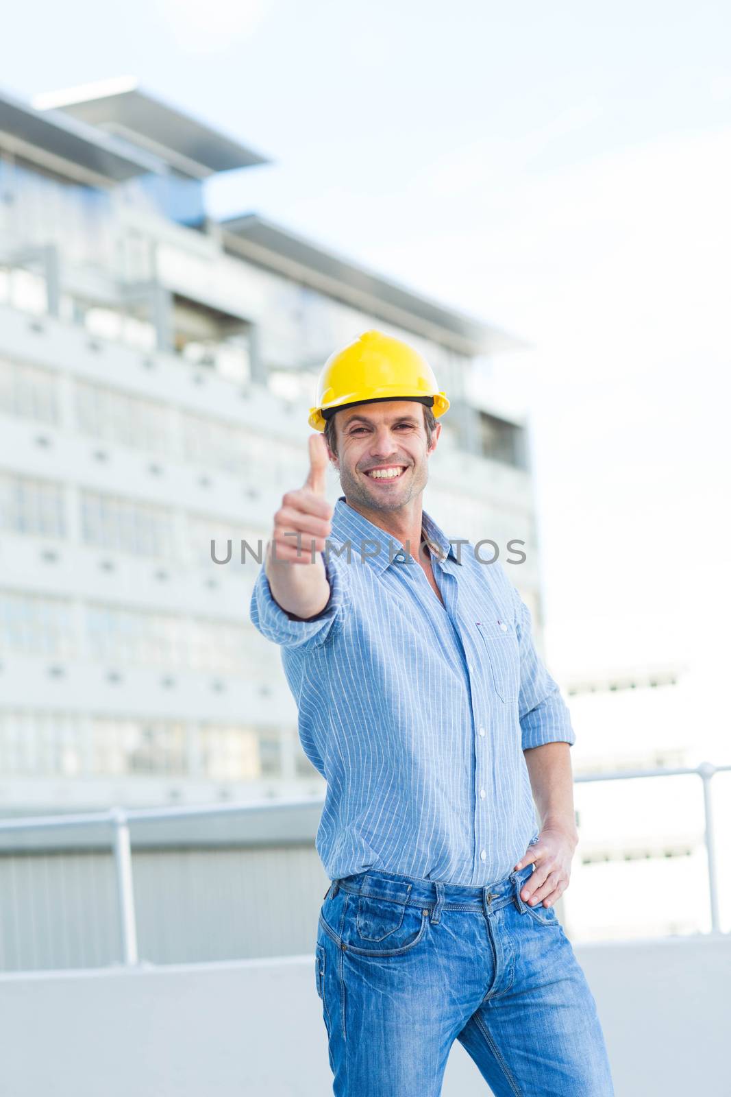 Portrait of smiling male architect gesturing thumbs up outdoors