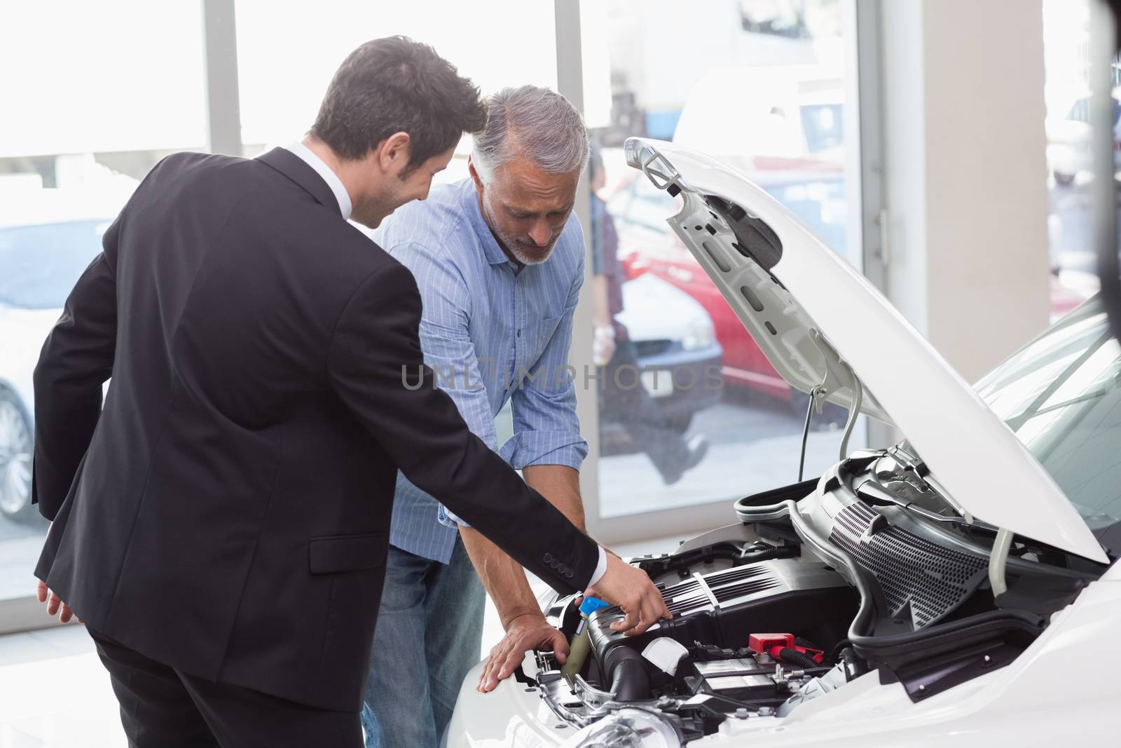 Two men looking at a car engine at new car showroom