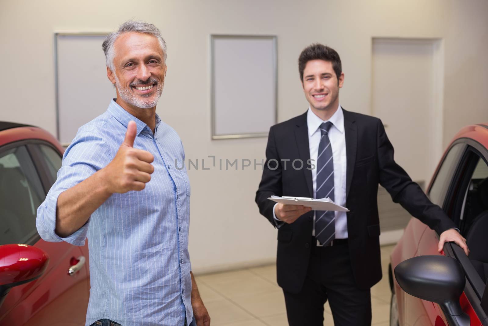 Smiling customer giving thumbs up at new car showroom