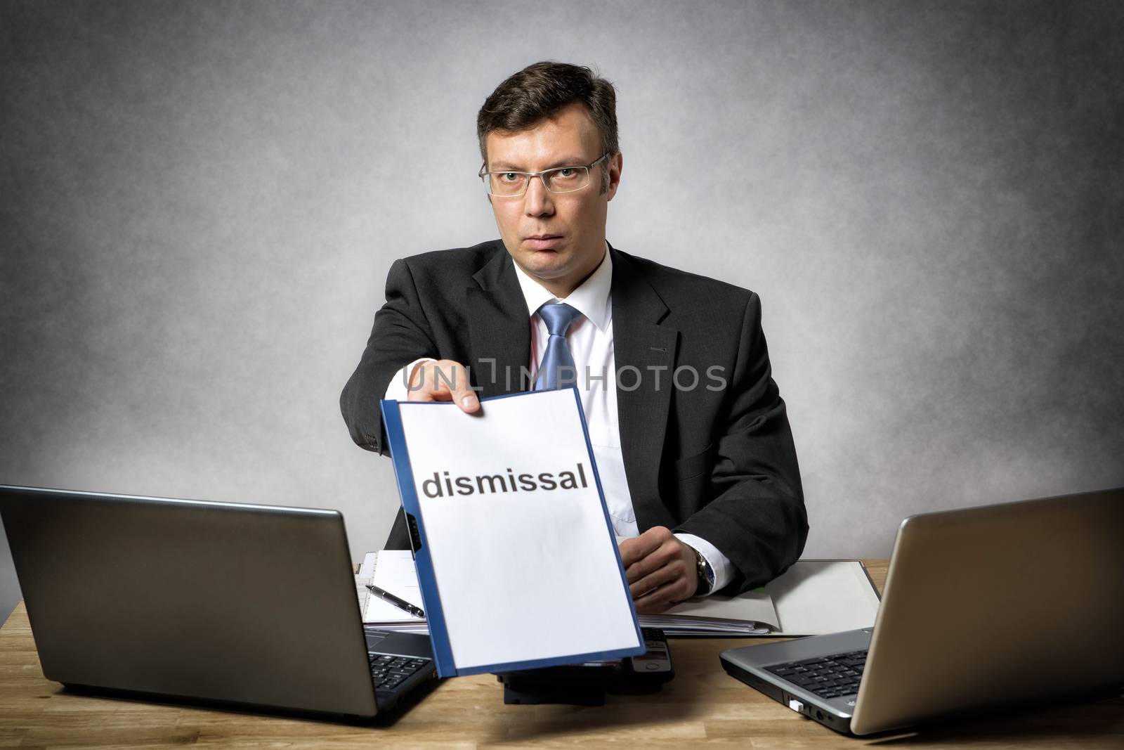 Boss sitting at the desk in office dismiss somebody