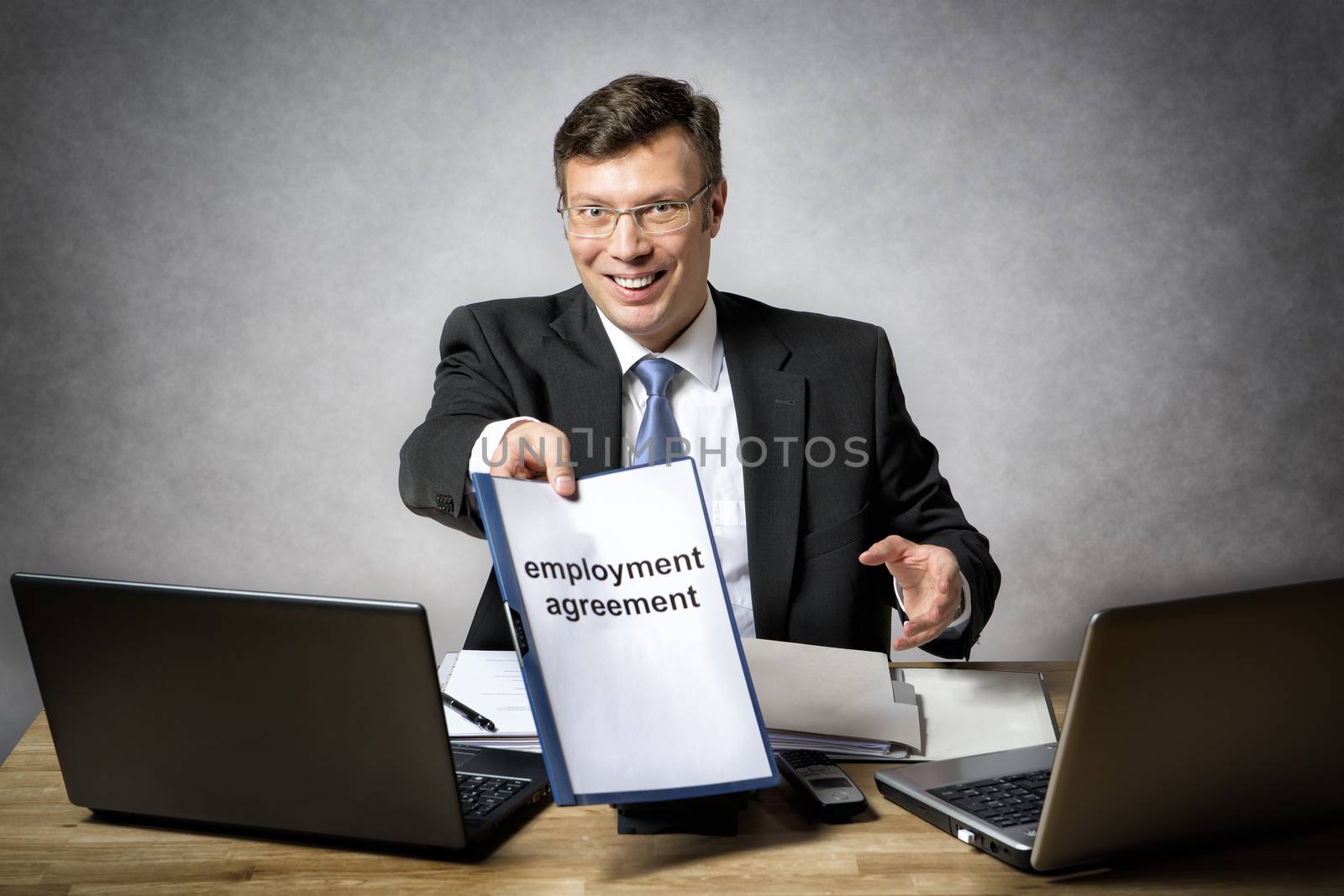 Boss sitting at the desk in office gives somebody a employment agreement