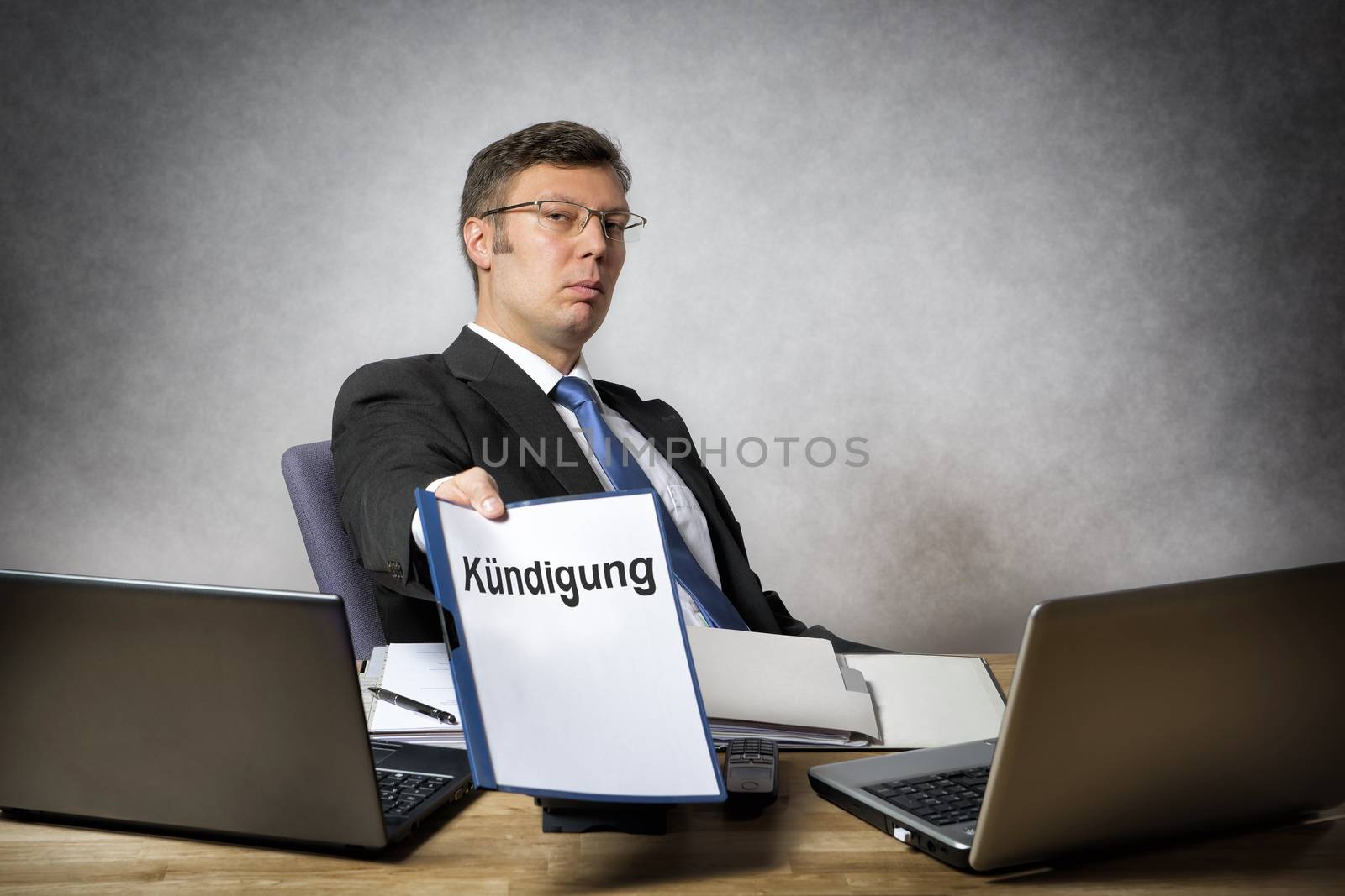 Boss sitting at the desk in office dismiss somebody with german paper