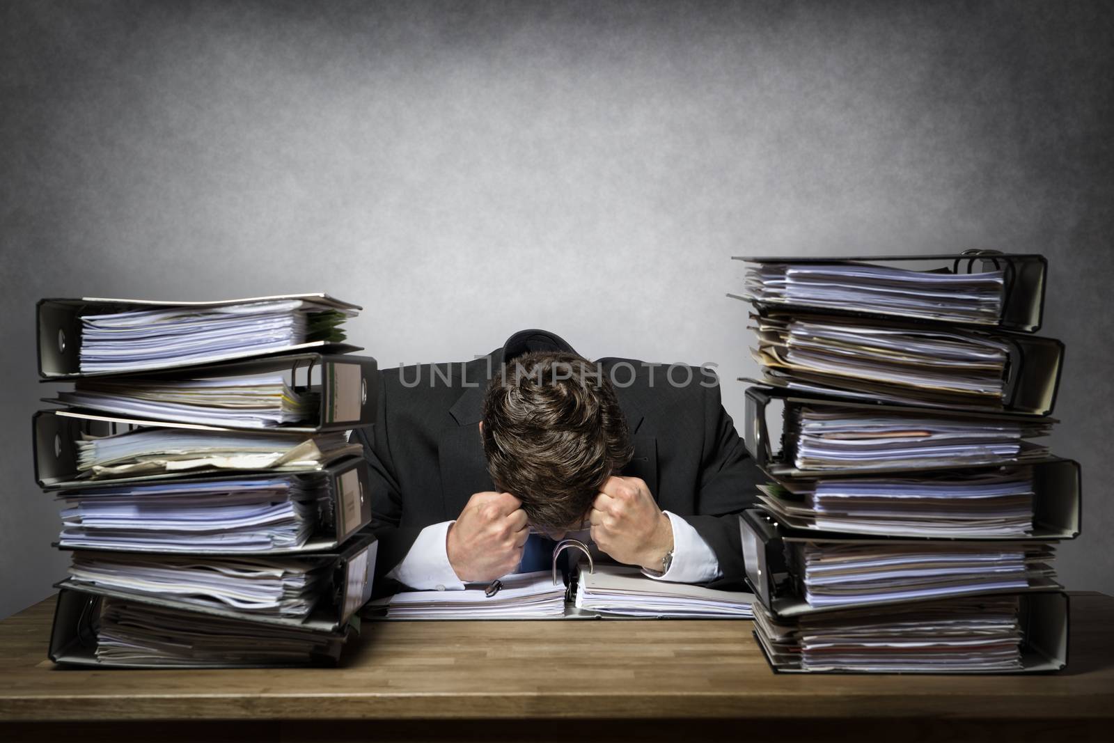 Overworked frustrated businessman with lot of files on his desk