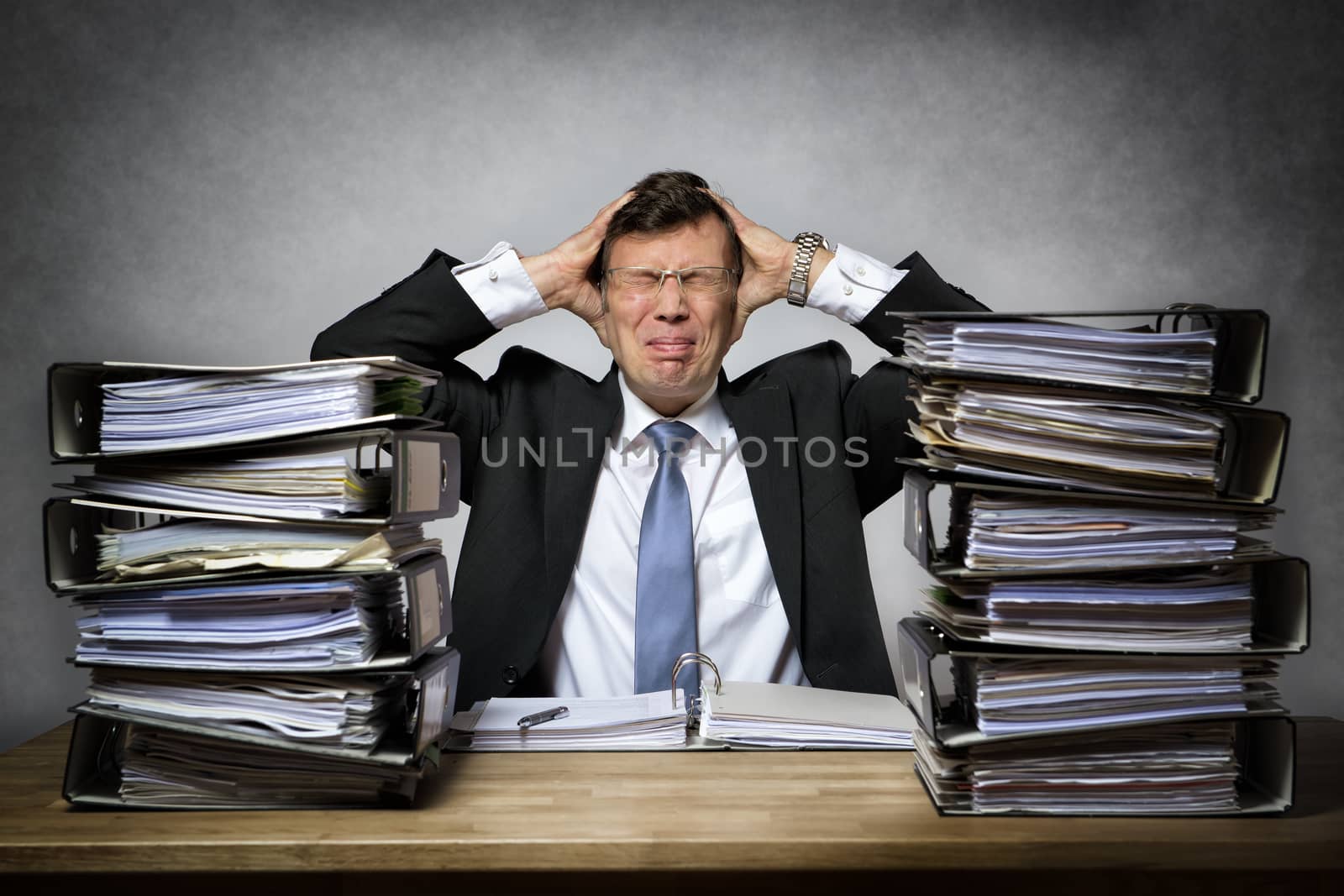 Overworked stressed businessman with lot of files on his desk