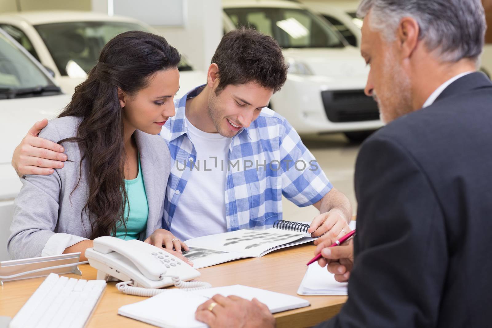 Smiling couple reading a booklet by Wavebreakmedia