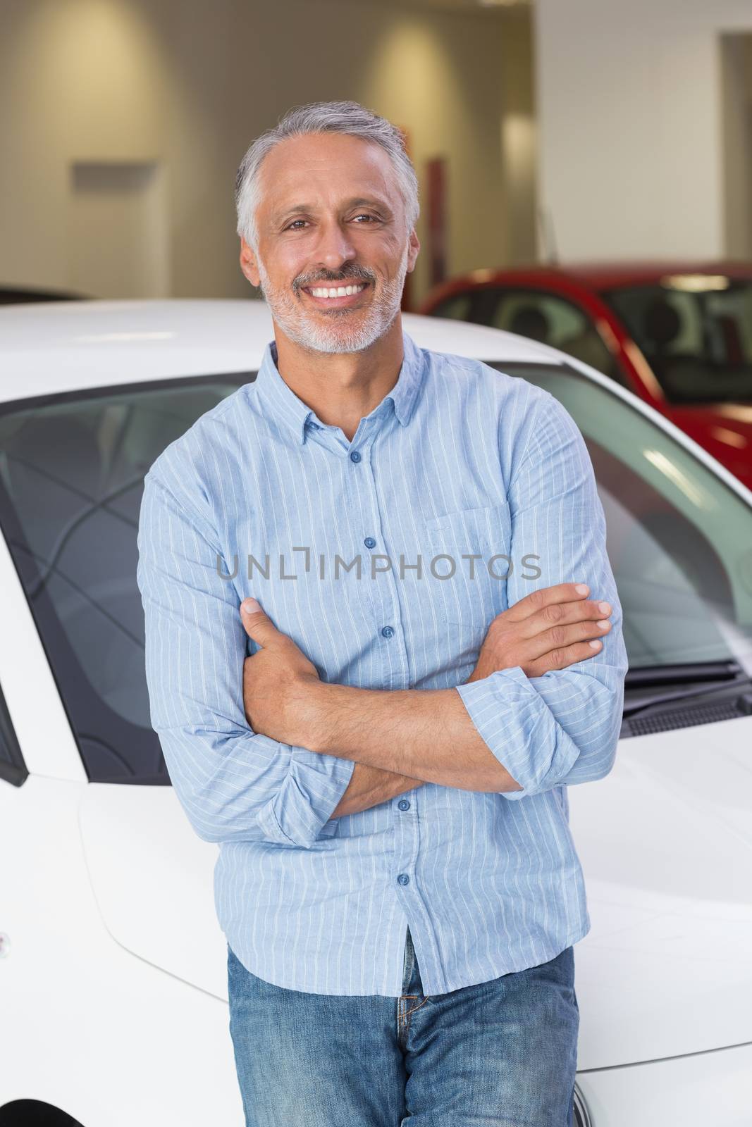 Smiling customer leaning on car with arms crossed by Wavebreakmedia