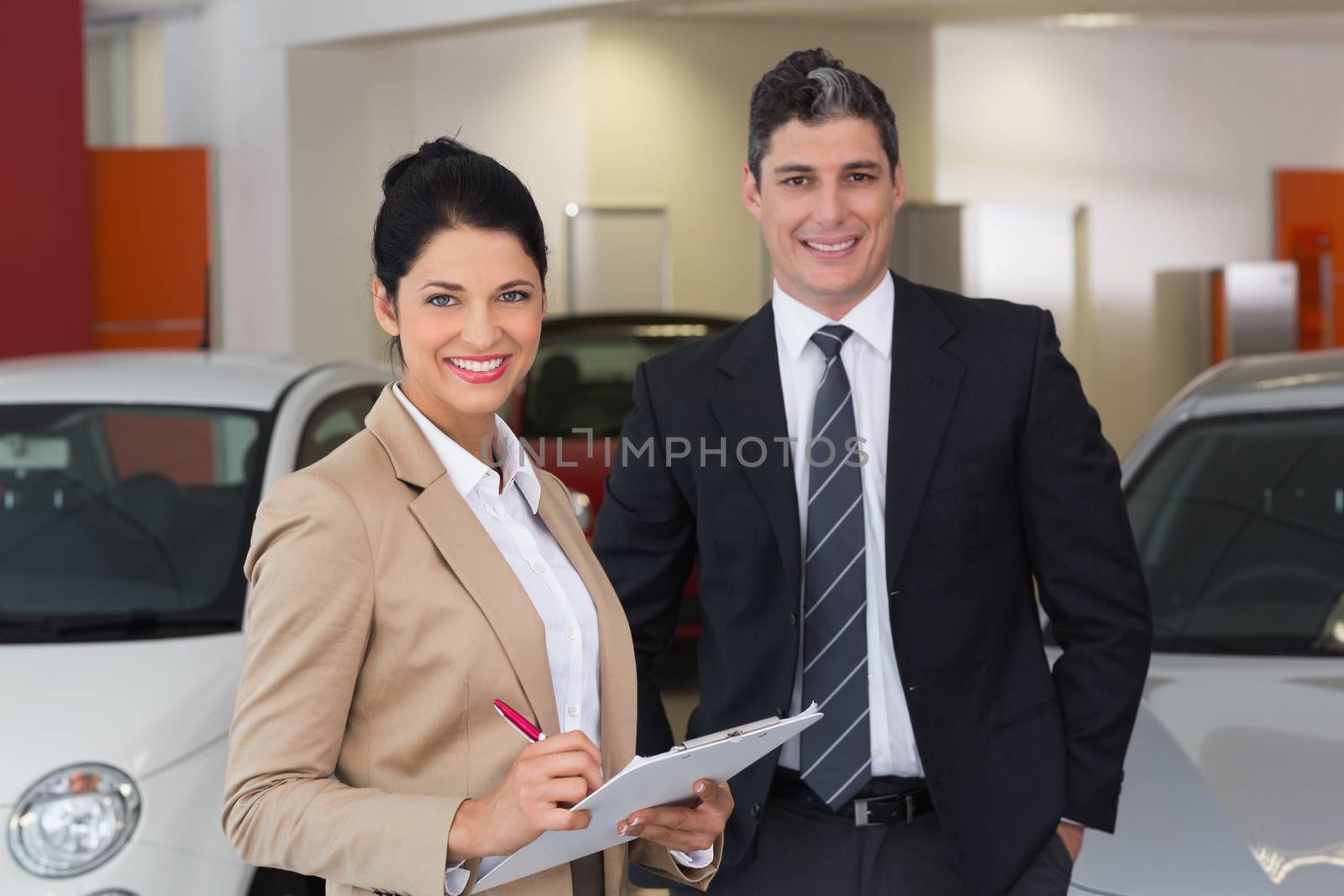Business team smiling at camera at new car showroom