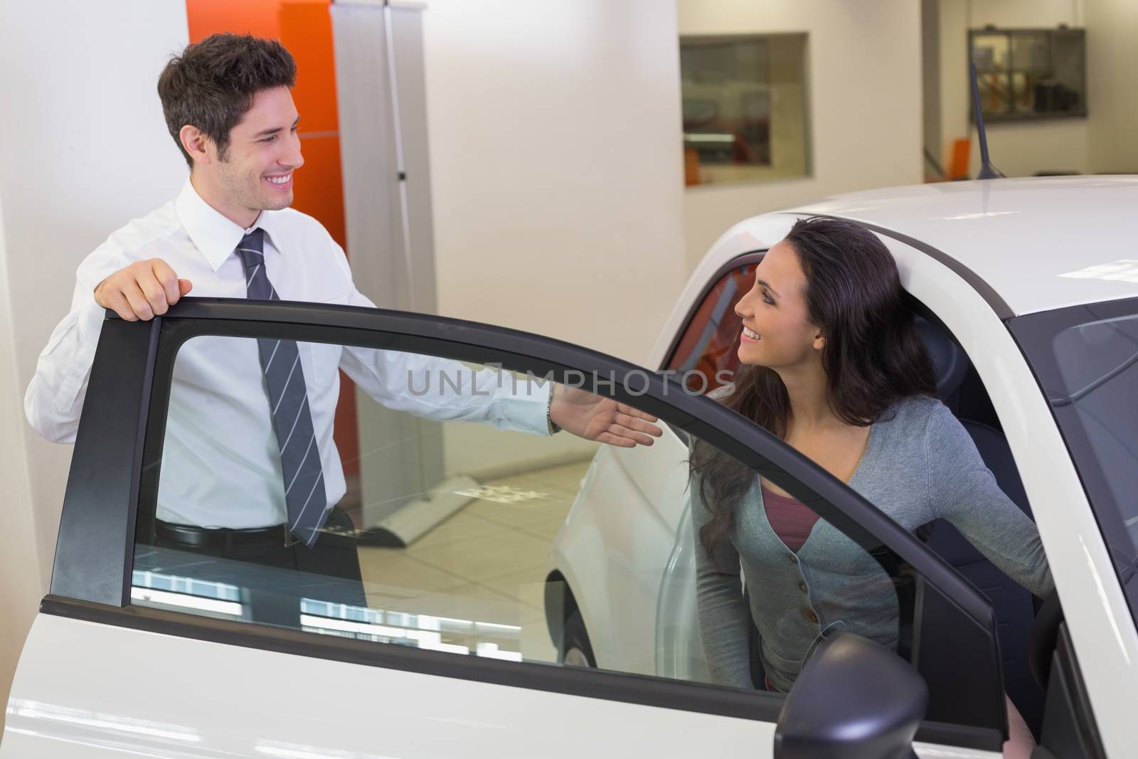 Salesperson speaking with happy client at new car showroom