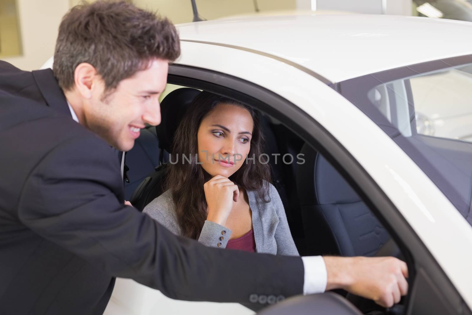Businessman showing something to his customer at new car showroom