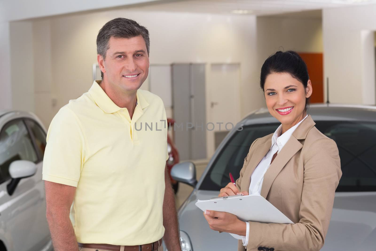 Smiling businessman undersign a car contract at new car showroom