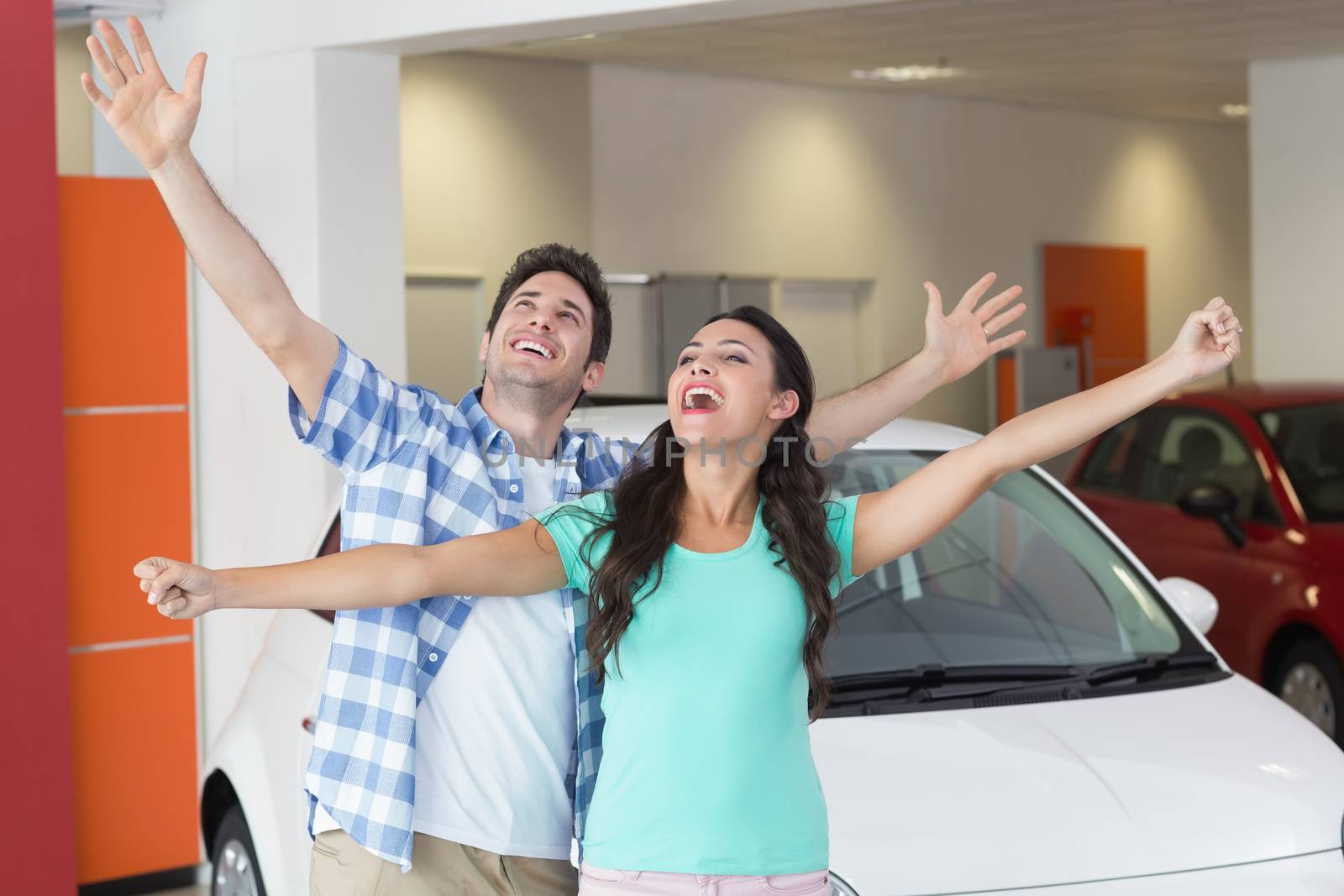 Young couple smiling and cheering at new car showroom