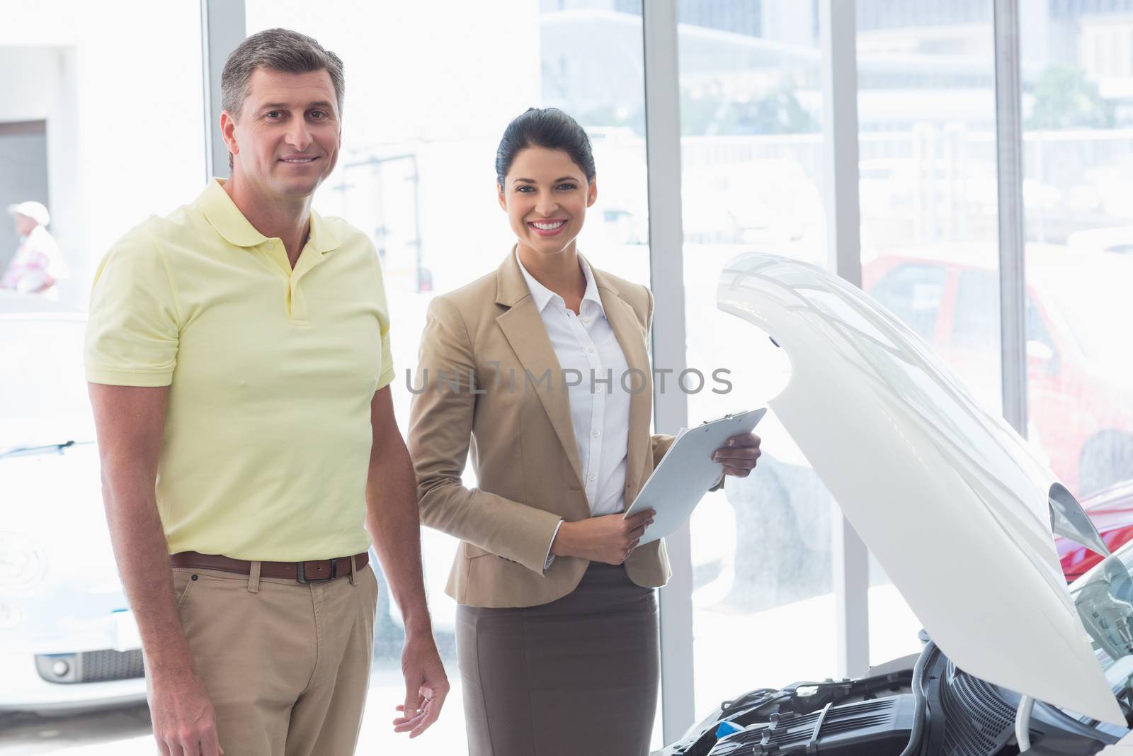 Businesswoman and customer looking at a car engine at new car showroom