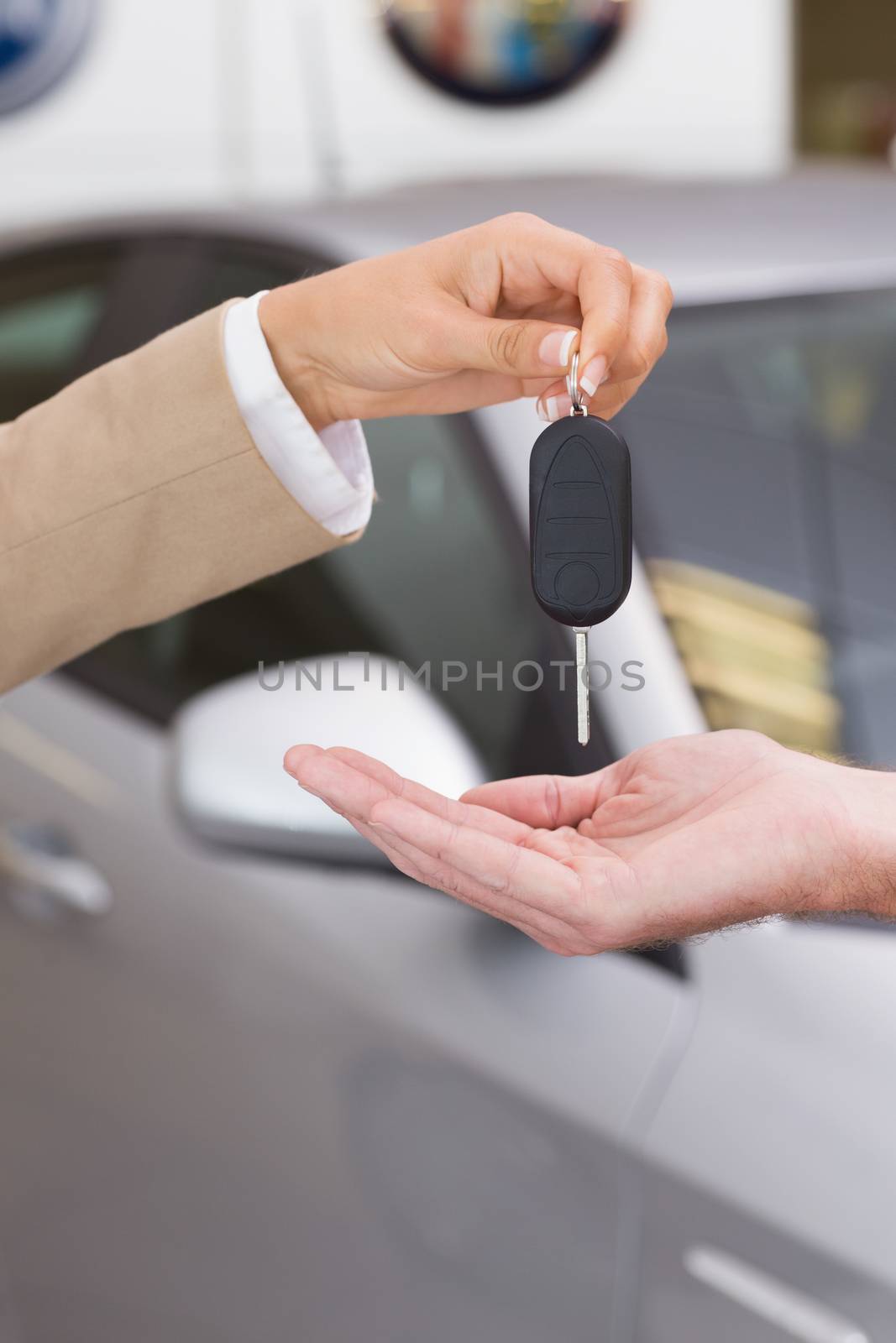 Businesswoman giving car key to happy customer at new car showroom
