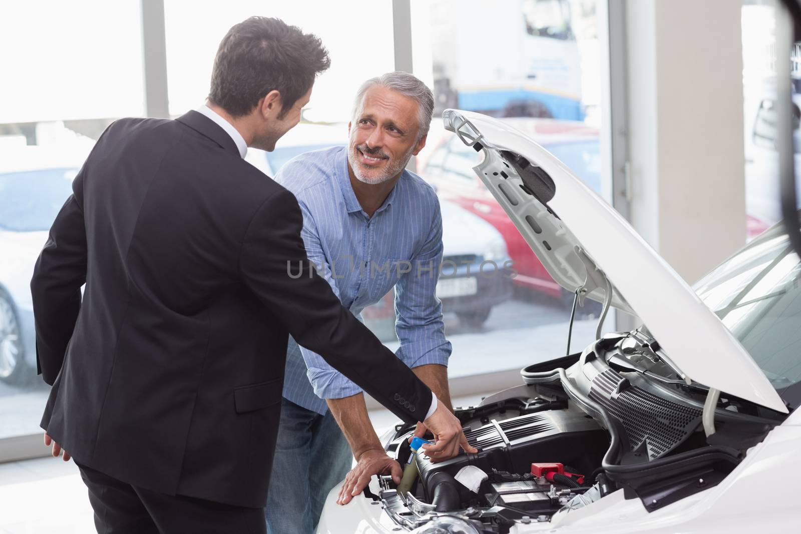 Two men looking at a car engine at new car showroom