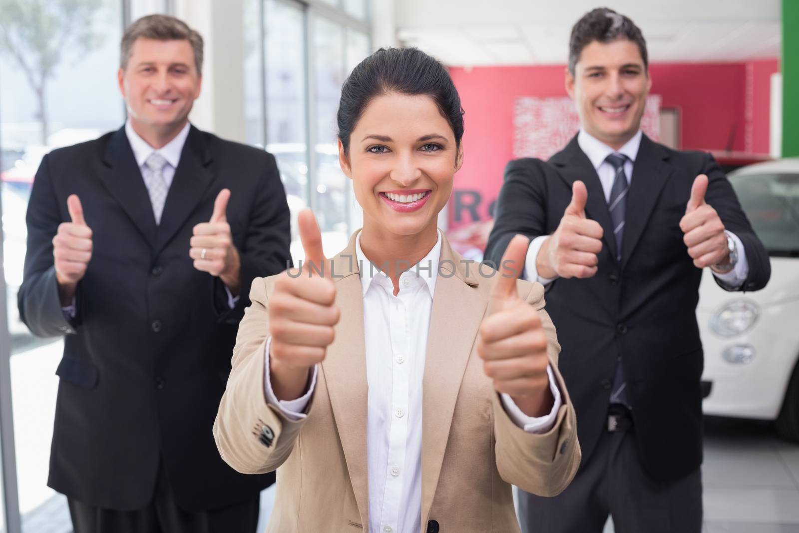 Smiling business team standing while giving thumbs up by Wavebreakmedia