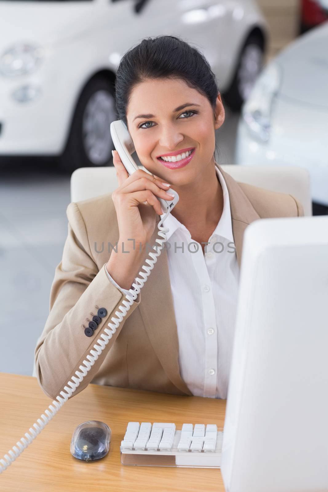 Smiling businessman making a phone call at new car showroom