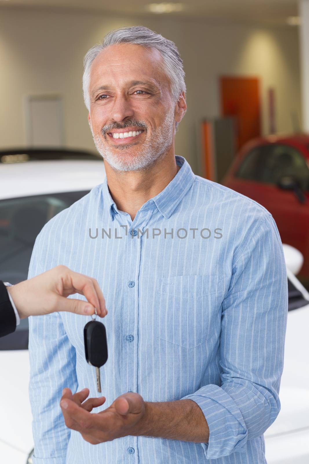 Businessman giving car key to happy customer at new car showroom