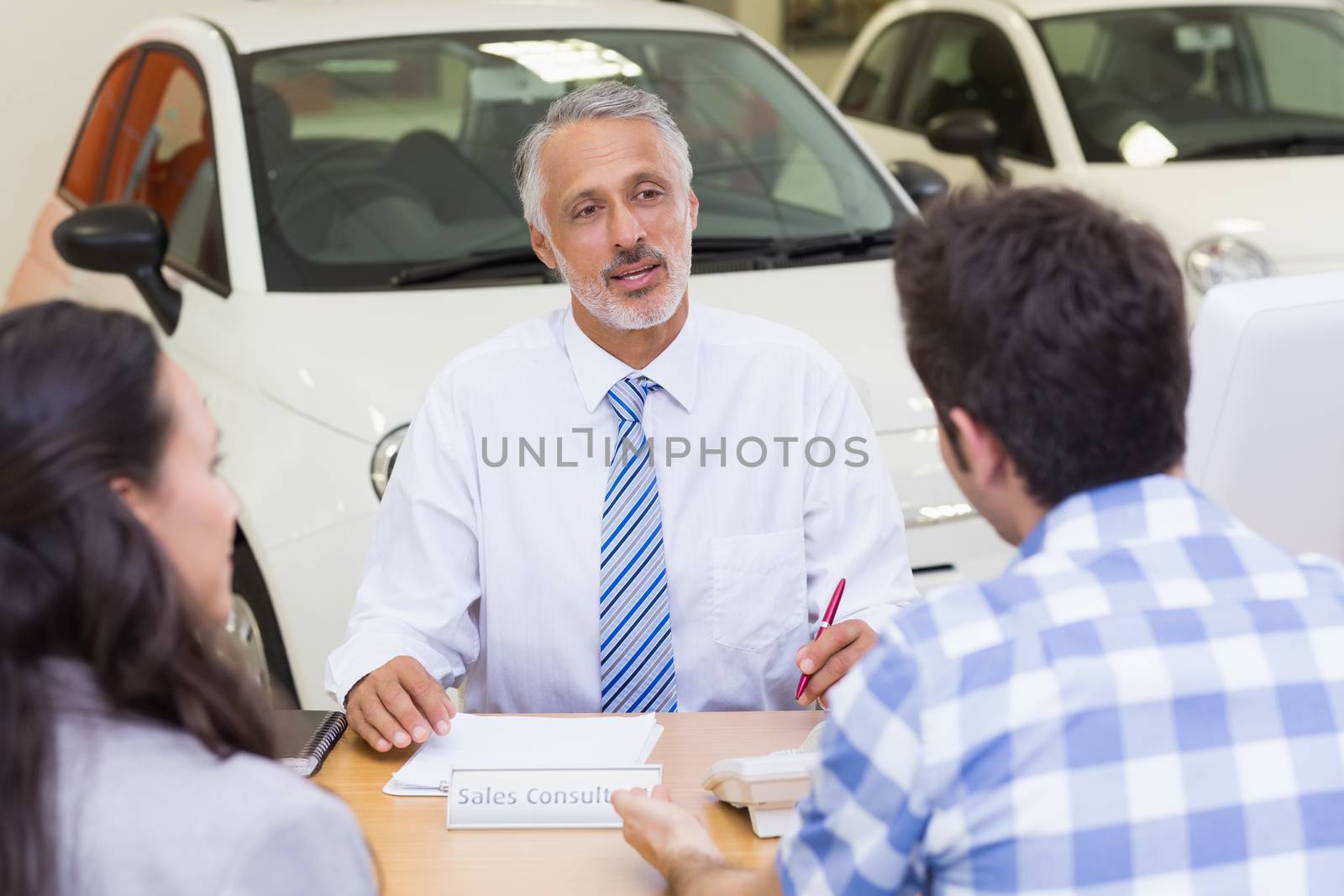 Clients talking with a dealer at new car showroom