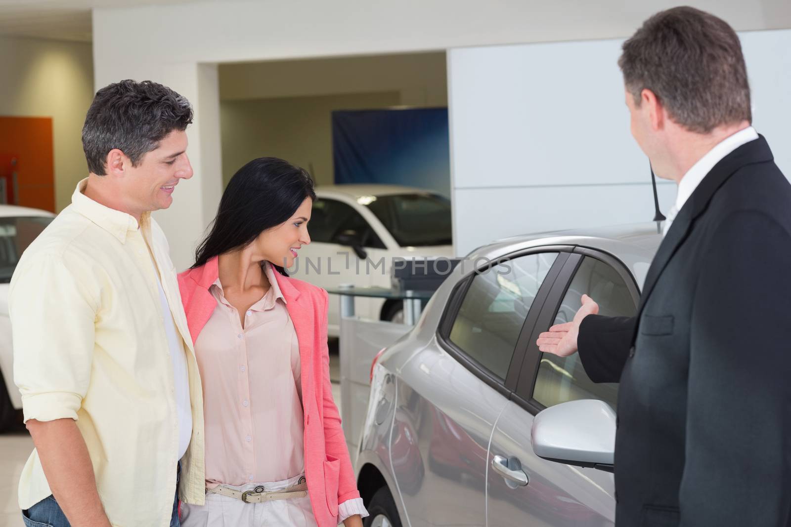 Businessman showing a car to a couple by Wavebreakmedia