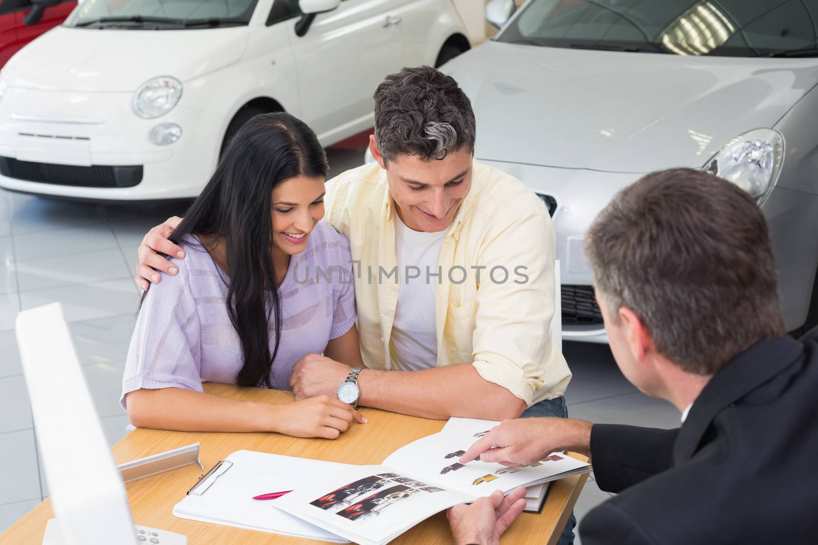 Salesperson pointing something on booklet at new car showroom