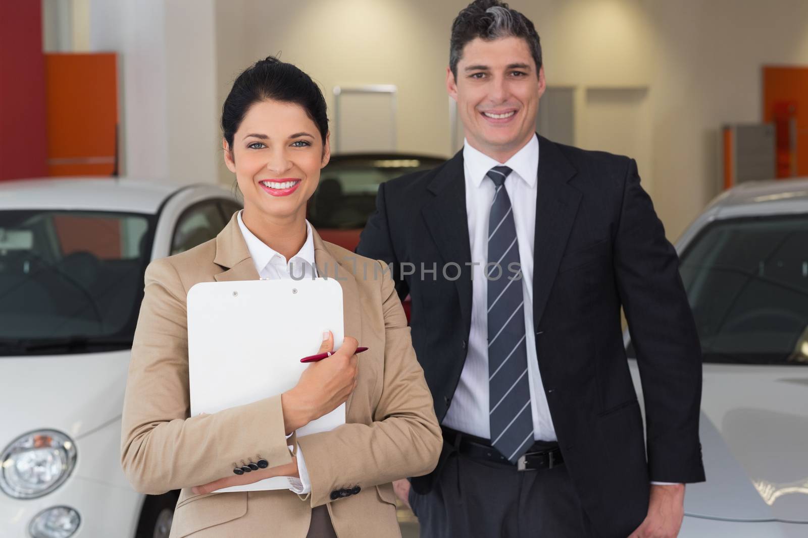 Business team smiling at camera at new car showroom