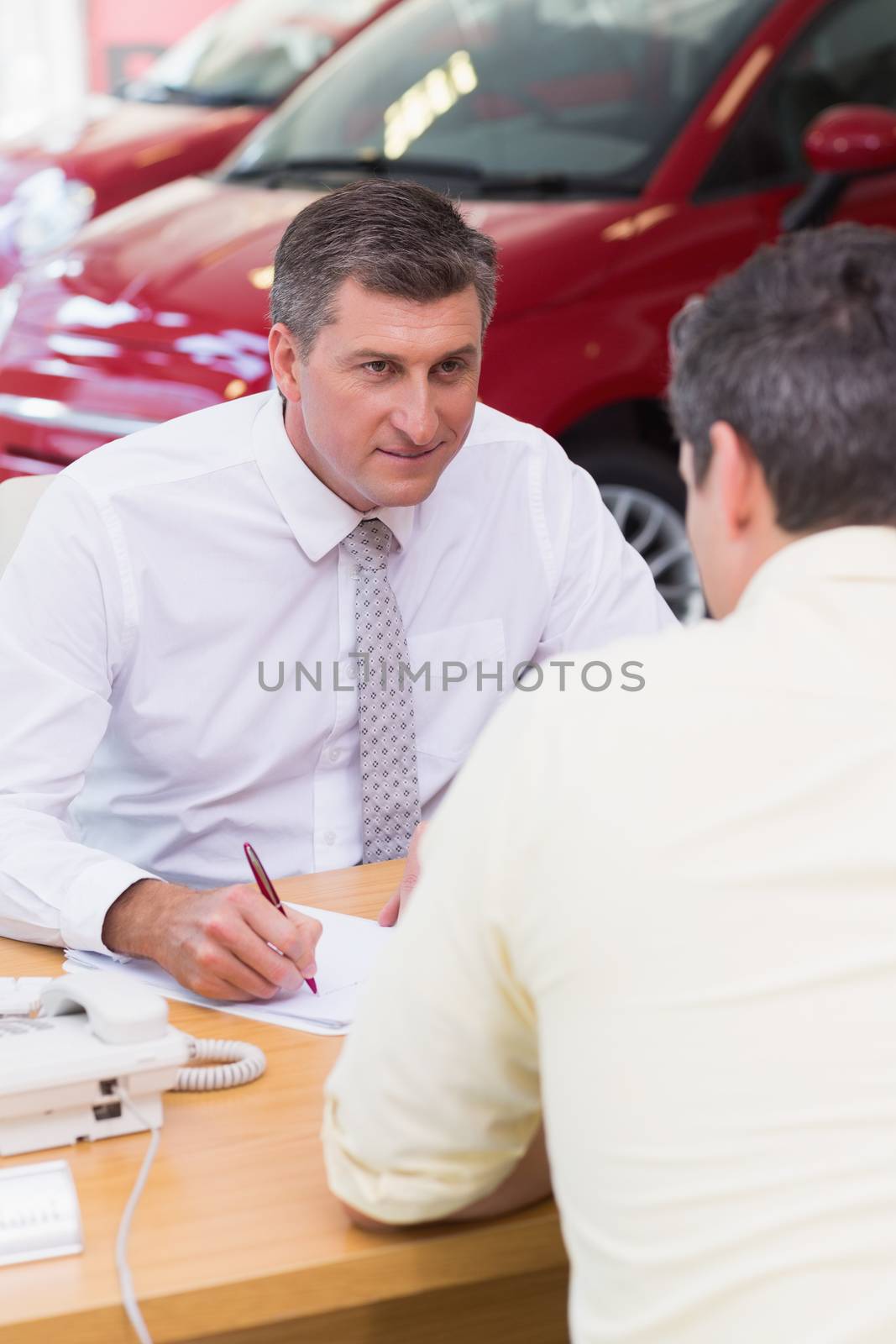 Smiling salesman writing on contract by Wavebreakmedia