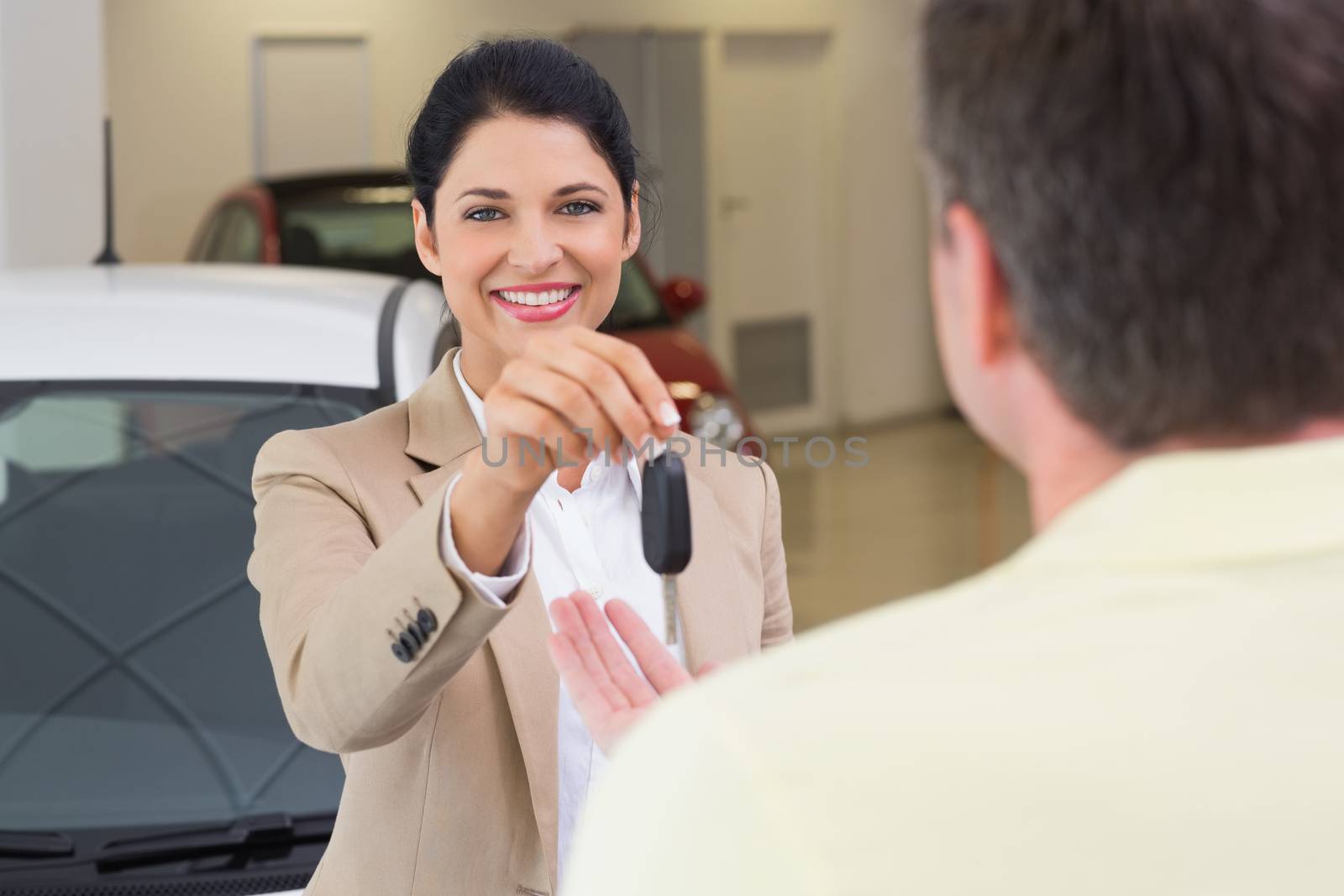 Smiling businesswoman giving car key to happy customer by Wavebreakmedia