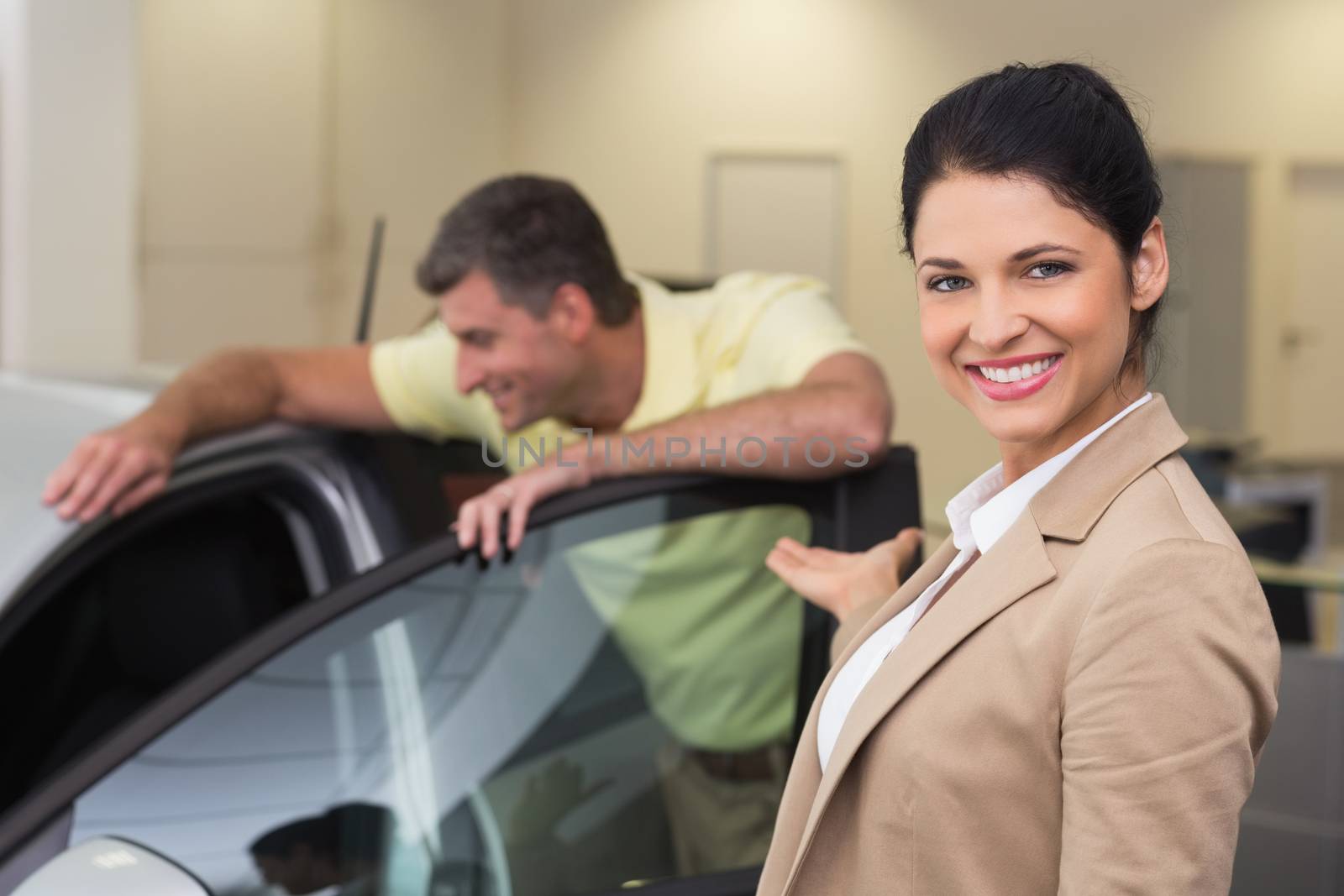 Businesswoman presenting a car to a client at new car showroom