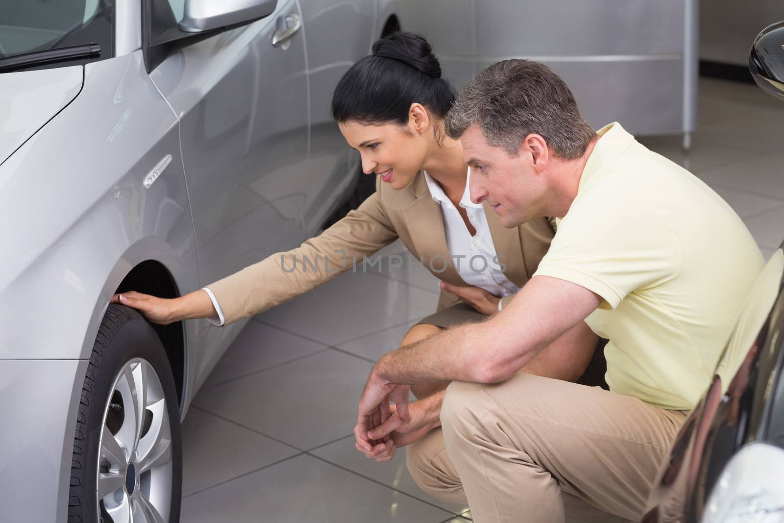 Businesswoman and customer discussing details of car tire by Wavebreakmedia