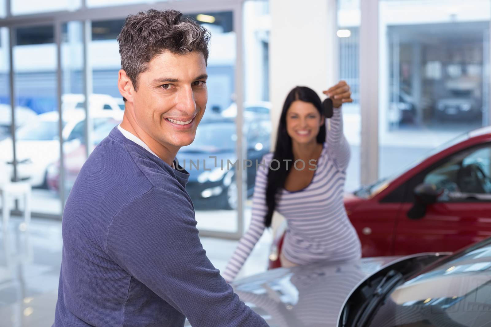 Smiling woman holding her new key at new car showroom