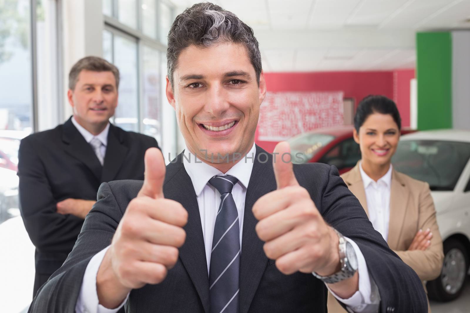 Smiling business team standing while one giving thumbs up by Wavebreakmedia