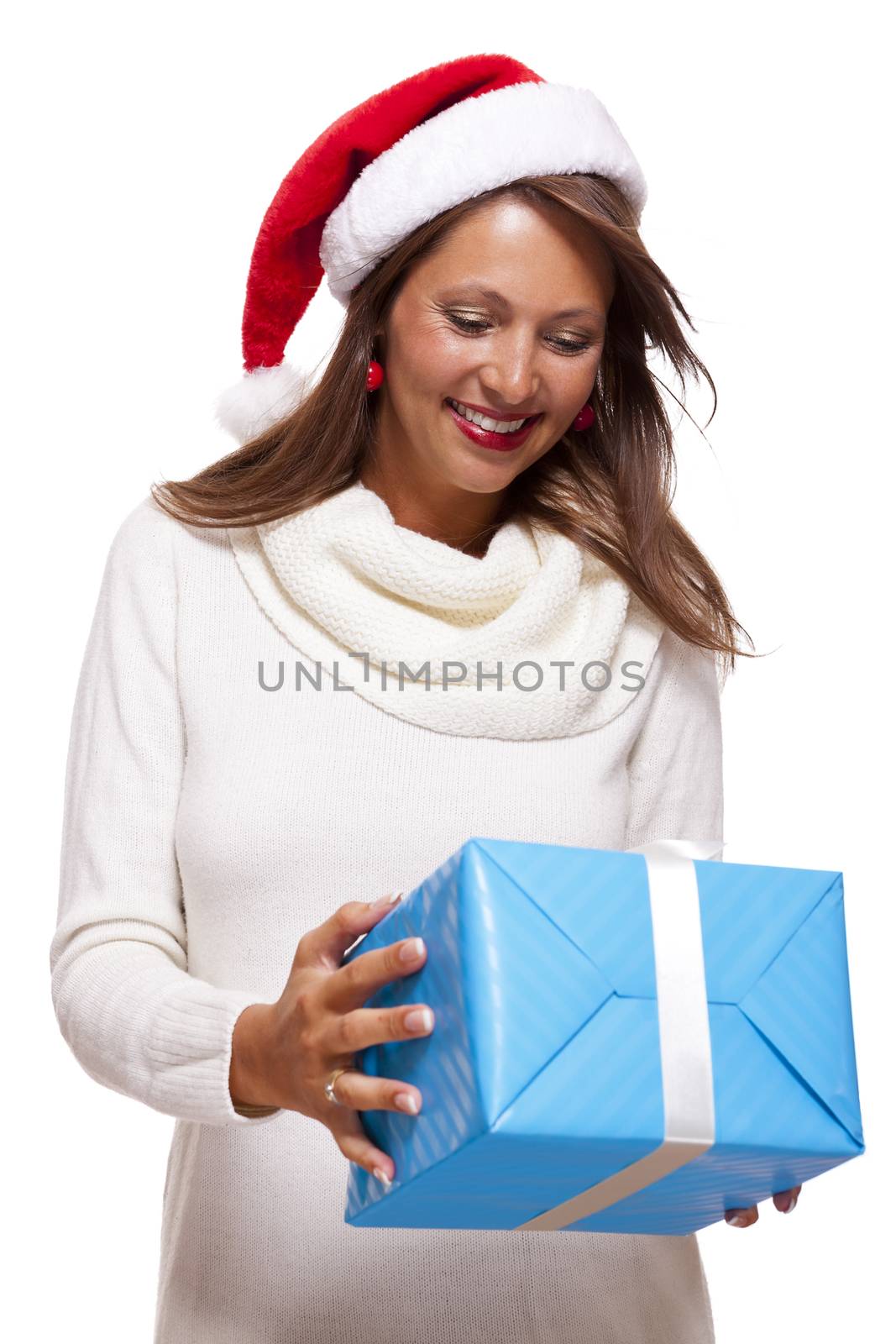 Beautiful vivacious woman wearing a red Santa hat laughing and holding up a gift-wrapped blue Christmas gift as she celebrates the festive season, on white