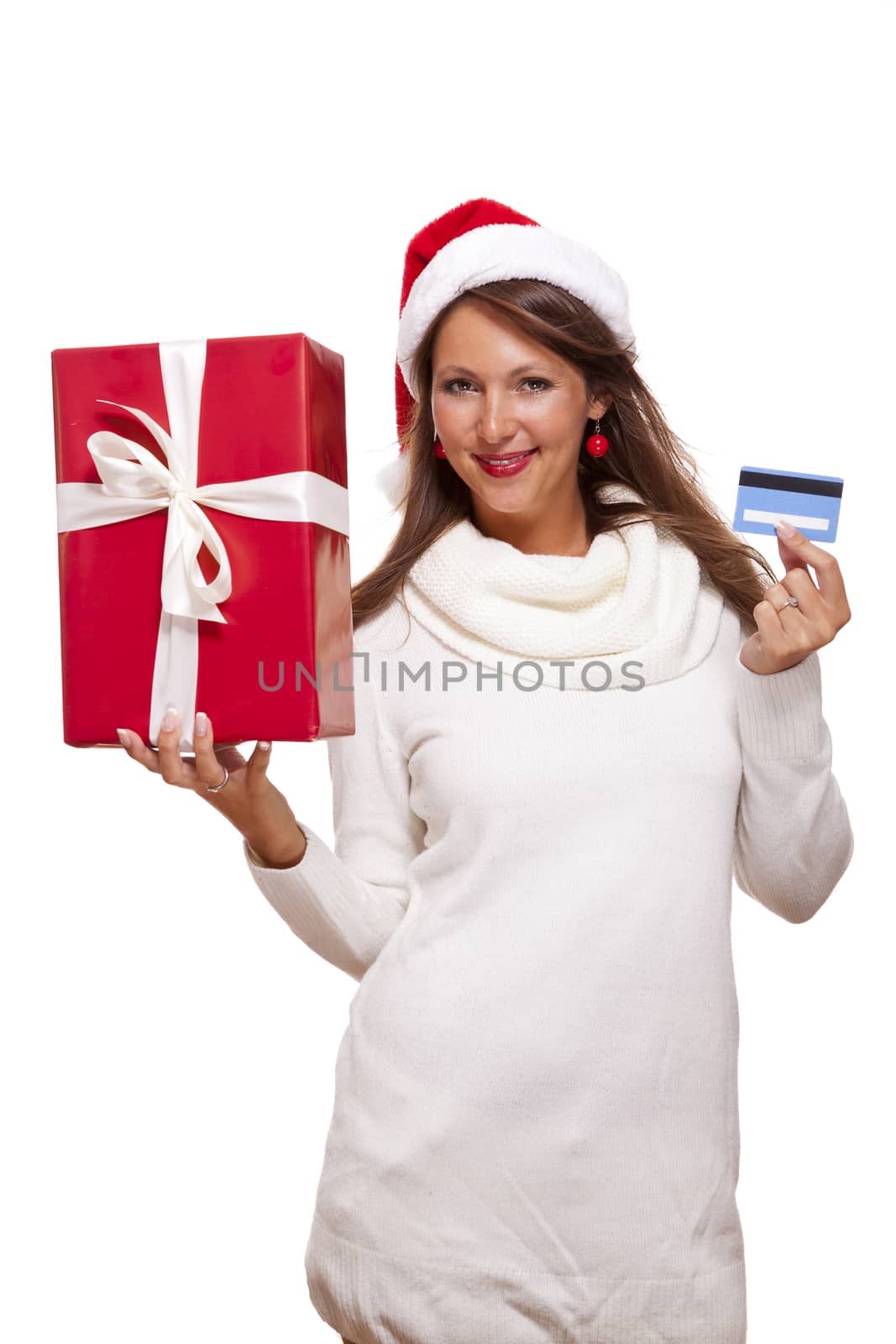 Attractive woman with a lovely smile wearing a red Santa hat holding a big red Christmas gift box and bank card as she celebrates her successful shopping spree