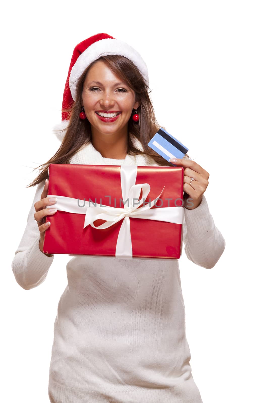 Attractive woman with a lovely smile wearing a red Santa hat holding a big red Christmas gift box and bank card as she celebrates her successful shopping spree