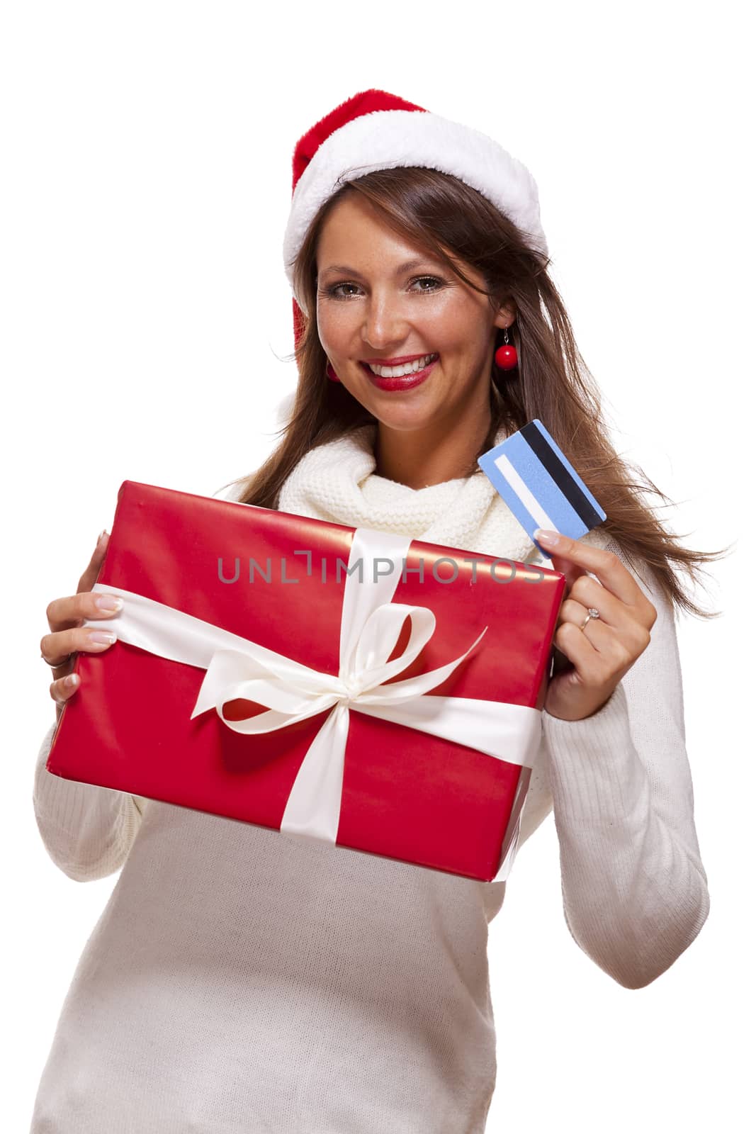 Attractive woman with a lovely smile wearing a red Santa hat holding a big red Christmas gift box and bank card as she celebrates her successful shopping spree