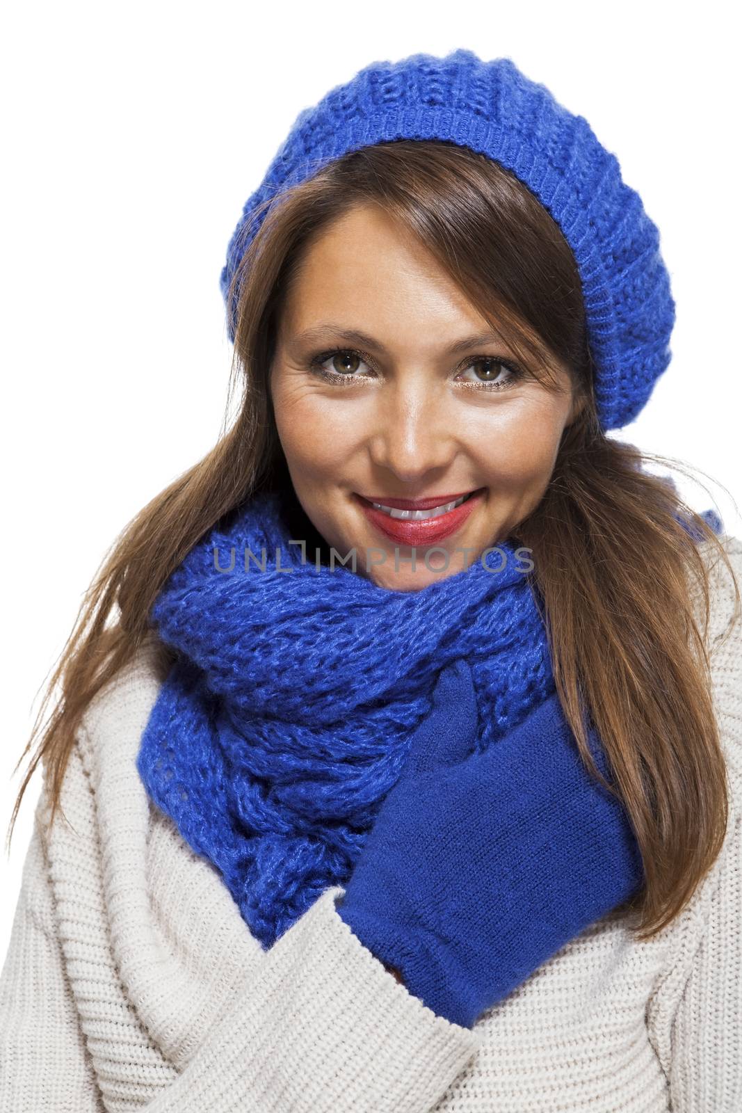 Close up Pretty Smiling Young Woman Wearing Winter Knit Outfit with Blue Bonnet, Scarf and Gloves. Captured in Studio with White Background While Looking at the Camera.