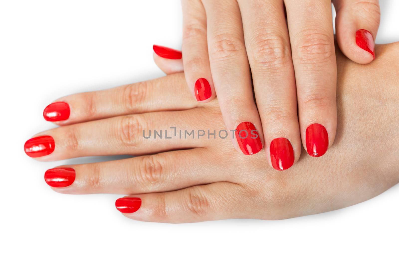 Woman with beautiful manicured red fingernails gracefully crossing her hands to display them to the viewer on a white background in a fashion, glamour and beauty concept