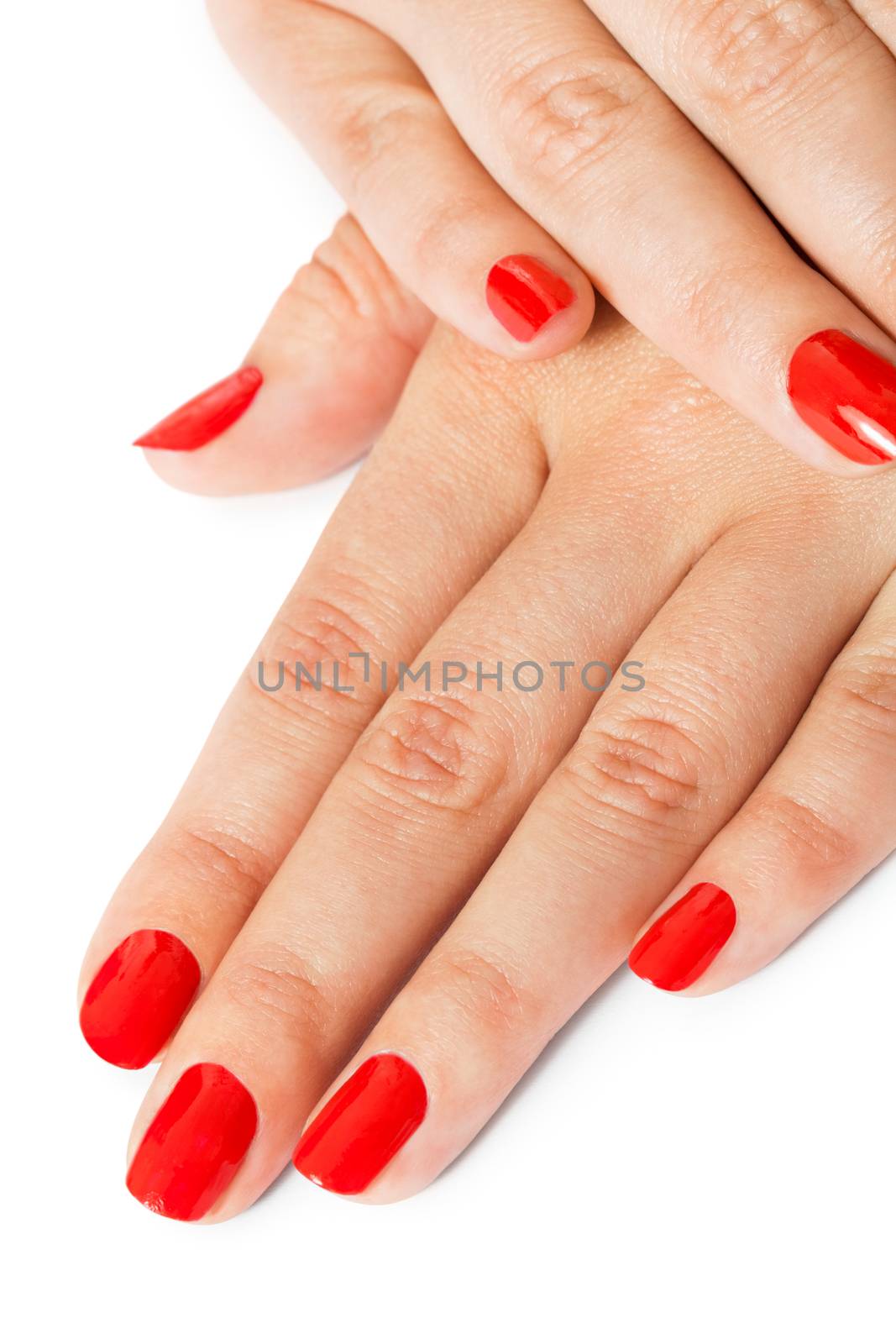 Woman with beautiful manicured red fingernails gracefully crossing her hands to display them to the viewer on a white background in a fashion, glamour and beauty concept