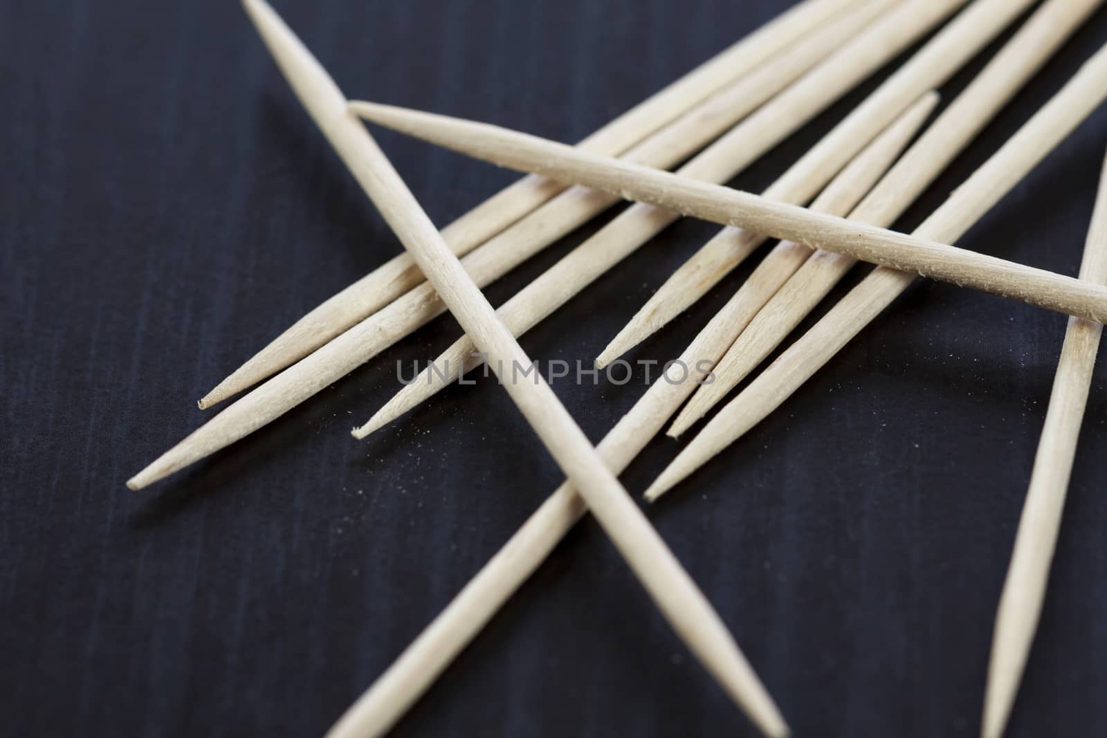 Pile of wooden toothpicks scattered randomly on a grey background for cleaning between the teeth after a meal in a personal hygiene concept