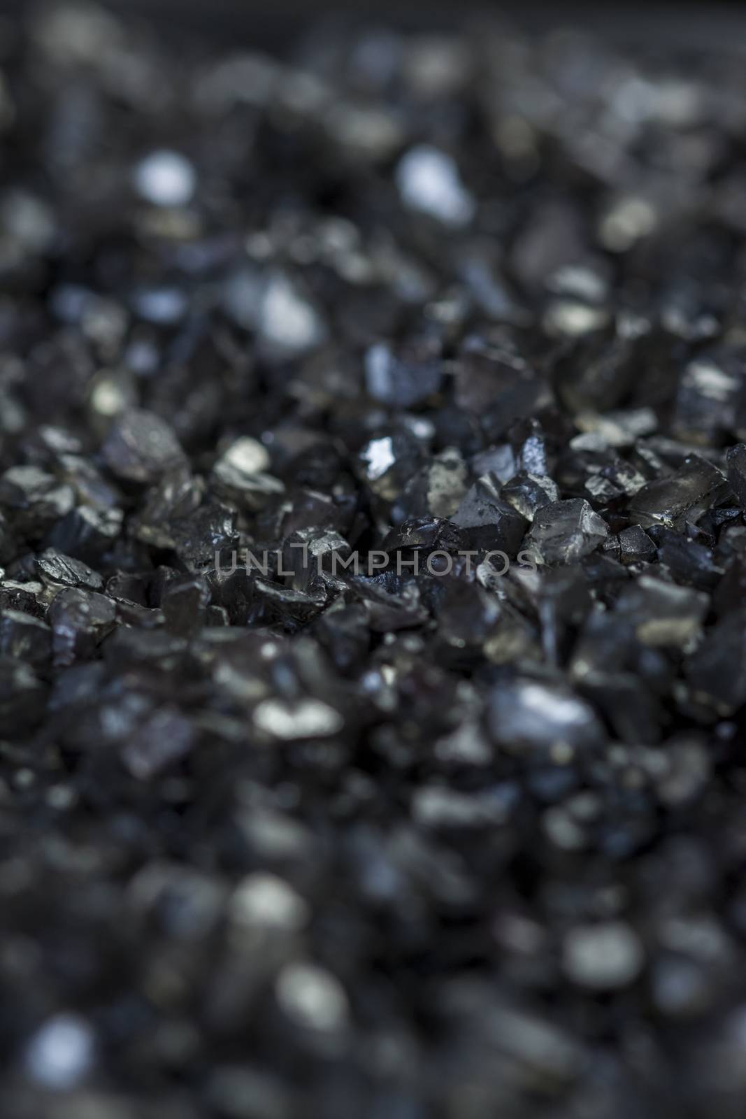 Background texture of an asphalt or tarmac road surface showing the tiny stones in the gravel with shallow dof